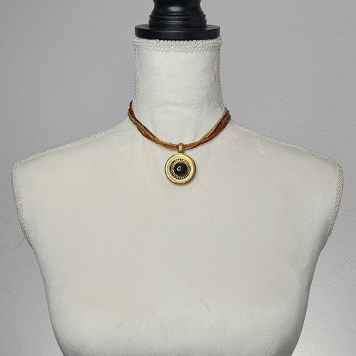 Gold beaded necklace with gold tone center stone medallion.